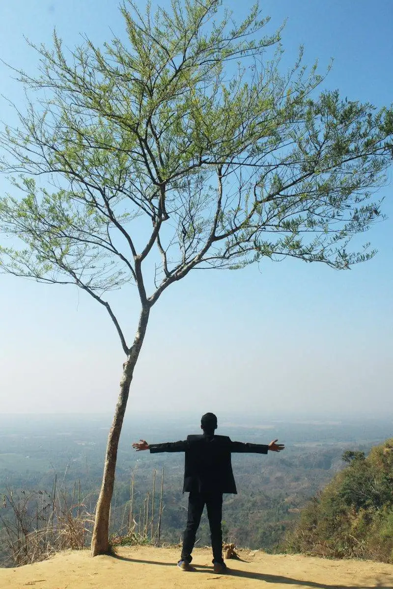 Homme ouvrant les mains devant la nature, symbolisant l'épanouissement et la confiance en soi grâce aux soft skills.