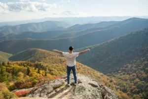 Soft skills – homme ouvrant les mains devant la nature, symbolisant l’épanouissement personnel et la confiance en soi